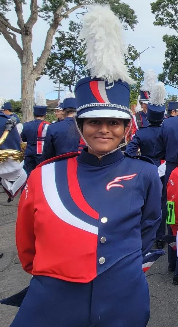 Isha in American High School marching band uniform, wearing the plumed shako.