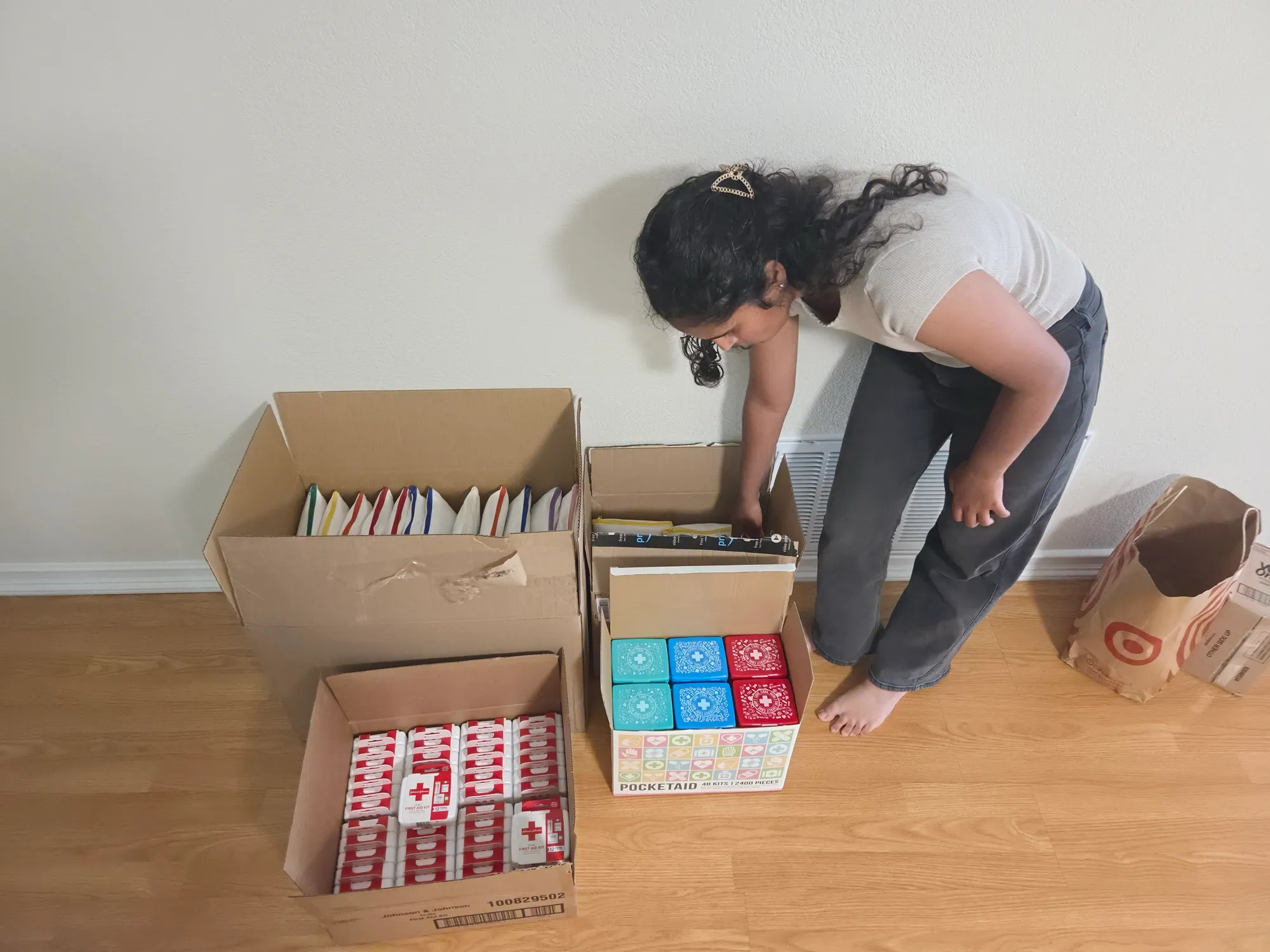 Sorting boxes of first aid kits and supplies on the floor before assembly.